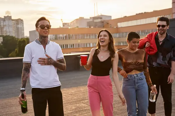 Drunk jolly friends in casual vivid attires holding alcohol drinks and having fun at rooftop party — Stock Photo