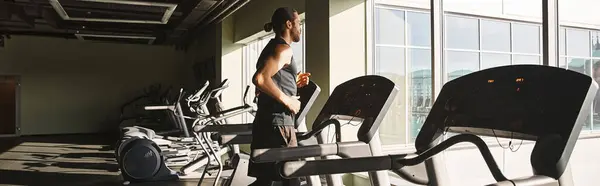 Um homem em forma no desgaste atlético está ao lado de uma fileira de bicicletas de exercício em um ginásio. — Fotografia de Stock