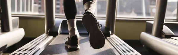 Un hombre atlético en ropa activa caminando en una cinta de correr en un gimnasio. - foto de stock