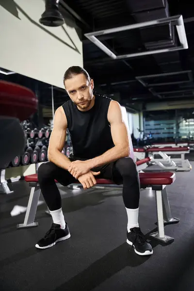 An athletic man in workout gear sitting on a gym bench, taking a break from his vigorous training routine. — Stock Photo