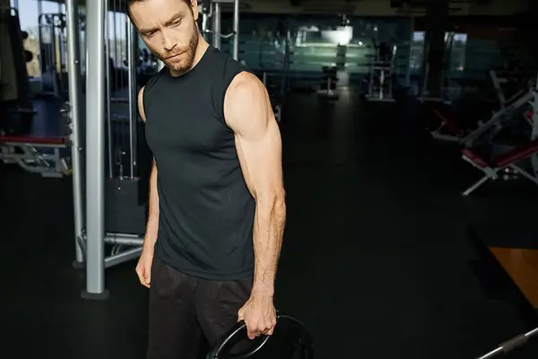 Un atlético en ropa activa sosteniendo una placa negra en un gimnasio. - foto de stock
