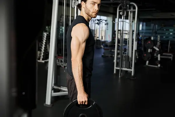Un homme concentré en tenue de gymnastique tenant un haltère, montrant détermination et force pendant sa routine d'entraînement. — Photo de stock