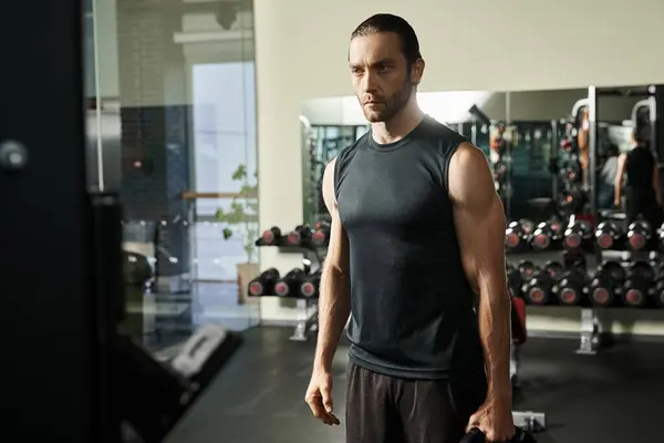 Підходить чоловік у спортивному одязі стоїть у спортзалі, тримаючи чорні тарілки — стокове фото
