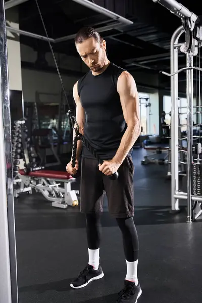Un homme concentré et athlétique en tenue active se tient en confiance au centre d'une salle de gym, prêt pour son entraînement. — Photo de stock