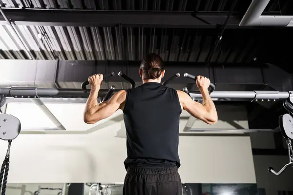 Un hombre en un gimnasio, vestido con ropa deportiva, levanta un bar ponderado durante su rutina de entrenamiento. - foto de stock