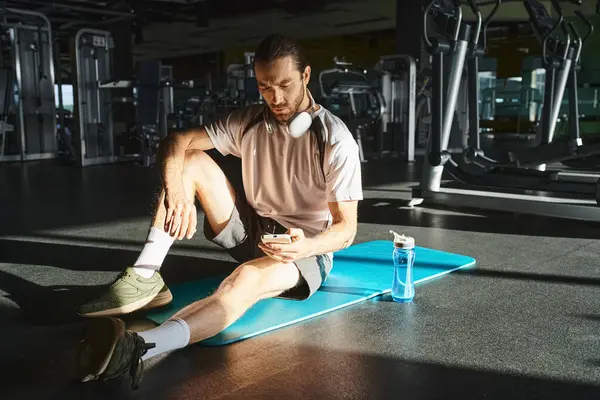 An athletic man in active wear is sitting on a blue mat in a gym. — Stock Photo