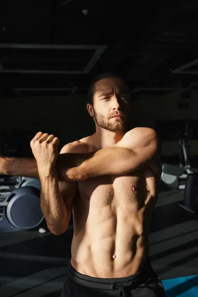 Un homme torse nu travaille avec diligence dans une salle de gym, concentré sur la sculpture de ses muscles grâce à la musculation. — Photo de stock