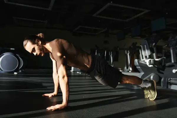 Ein muskulöser Mann ohne Hemd führt in einem Fitnessstudio fleißig Liegestütze durch, um seine Stärke und Hingabe zur Fitness zu demonstrieren. — Stockfoto