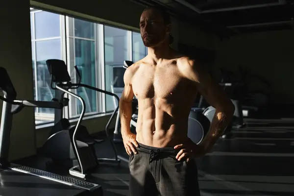 Un uomo muscoloso senza camicia davanti a una macchina da ginnastica, concentrato e pronto all'allenamento. — Foto stock