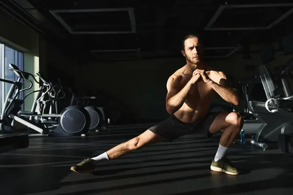 Мускулистый мужчина без рубашки, приседающий на одной ноге в спортзале. — стоковое фото
