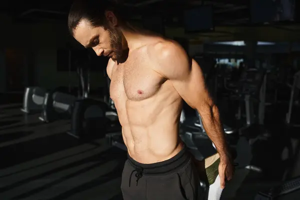 A muscular man without a shirt working out intensely in a gym, showcasing his strength and dedication. — Stock Photo