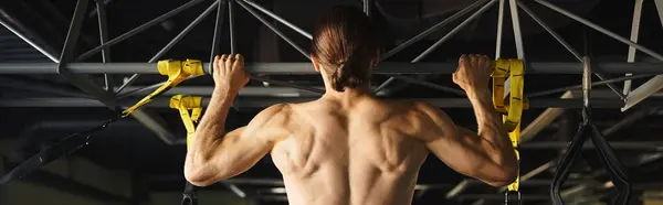 Homme musclé sans chemise montrant sa force tout en travaillant dans un cadre de gymnastique. — Photo de stock