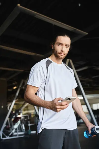 Ein Mann im weißen Hemd zückt nach dem Training im Fitnessstudio sein Smartphone — Stockfoto