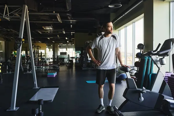 Un homme musclé debout dans une salle de gym entouré d'un rack d'équipement d'exercice. — Photo de stock