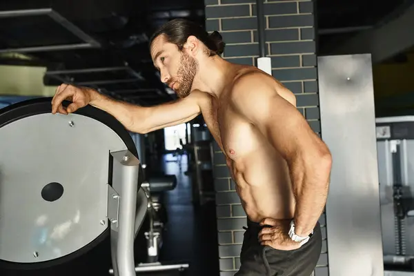 Shirtless muscular man holding onto machine, focused on workout in gym. — Stock Photo