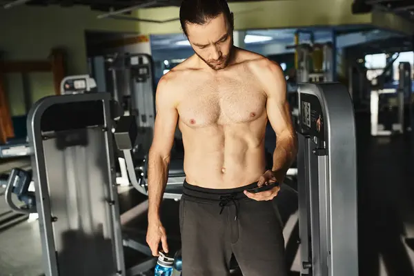 Ein muskulöser Mann mit einem Handy in der Hand in einem Fitnessstudio, nach dem Training in den sozialen Medien — Stockfoto