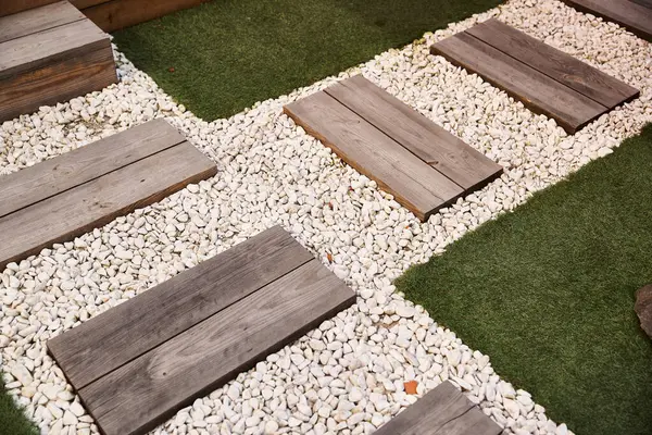 Uno spazio giardino sereno con gradini in legno che scendono verso un sentiero di ghiaia circondato da un verde lussureggiante ed elementi decorativi — Stock Photo