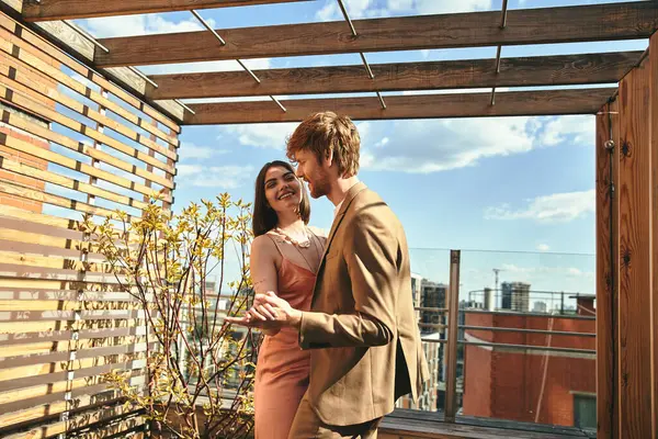 Ein Mann und eine Frau stehen am Rande eines Daches und blicken auf die Skyline der Stadt unter ihnen — Stockfoto