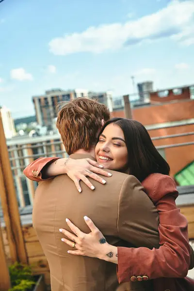 A woman and a man hugging affectionately on the rooftop of a building against a city skyline backdrop — Stock Photo