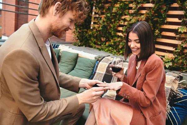 Una coppia gioiosa durante una proposta sul tetto, con l'uomo che offre un anello e la donna che irradia. — Foto stock