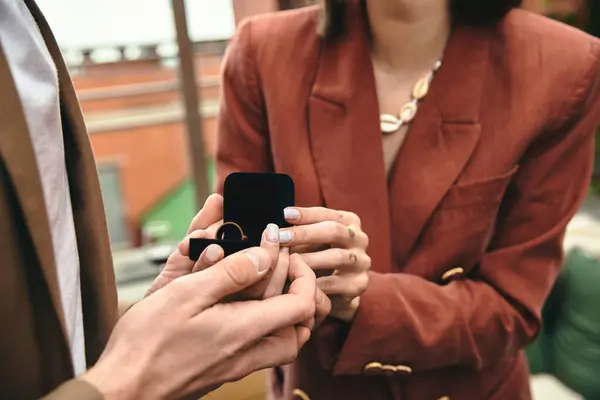 Eine Person auf gebeugten Knien bietet ihrem Partner einen Ring an, der einen herzerwärmenden Vorschlag festhält. — Stockfoto