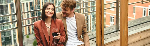 Um homem está graciosamente ao lado de uma mulher que segura um copo de vinho, exalando sofisticação e charme — Fotografia de Stock