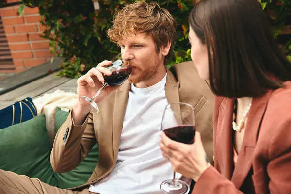 Um homem e uma mulher desfrutam de uma noite acolhedora em um sofá, bebendo vinho juntos — Fotografia de Stock