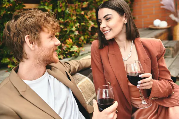 Un hombre y una mujer disfrutando de una copa de vino juntos en un entorno íntimo, compartiendo un momento de conexión y cercanía - foto de stock