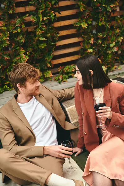 Un uomo e una donna trovano conforto mentre si siedono insieme su una panchina di legno, godendosi reciprocamente la compagnia e l'ambiente tranquillo — Foto stock