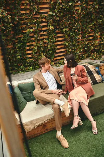 Un uomo e una donna si siedono insieme su un accogliente divano, immersi nella conversazione, circondati da calore e comfort — Foto stock