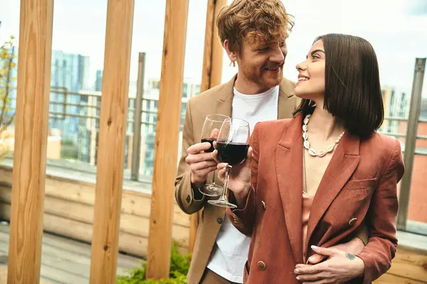 Un hombre y una mujer comparten un momento, de pie junto con copas de vino en la mano - foto de stock
