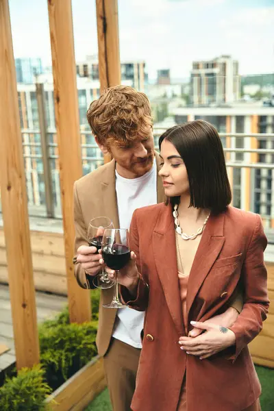 Um homem e uma mulher de pé graciosamente, ela segurando um copo de vinho. Eles exalam sofisticação e intimidade em seu momento compartilhado — Fotografia de Stock