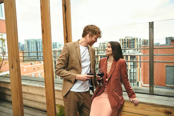 A man and woman are elegantly standing side by side, with the woman holding a wine glass — Stock Photo