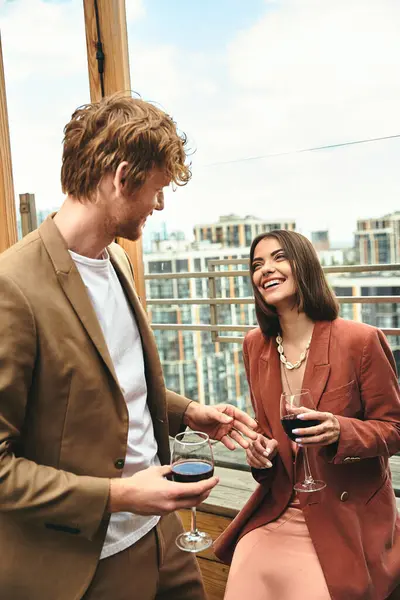 Un hombre y una mujer están uno al lado del otro, ella sostiene una copa de vino delicadamente. Exudan elegancia y sofisticación - foto de stock