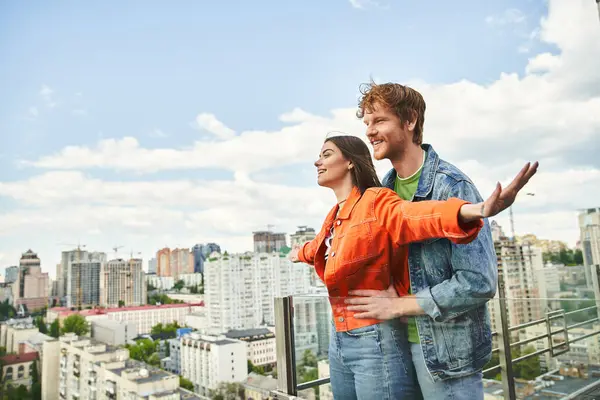 Чоловік і жінка впевнено стоять на вершині висотної будівлі, дивлячись на місто внизу з почуттям свободи і зв'язку — стокове фото