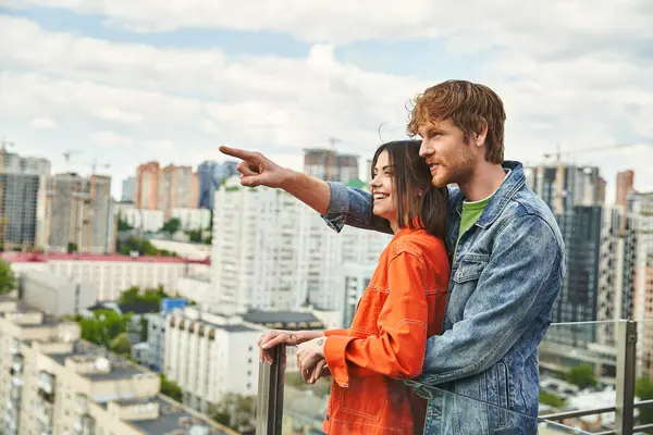 Un homme et une femme debout avec confiance sur le toit d'un bâtiment, regardant les toits de la ville avec crainte et détermination — Photo de stock