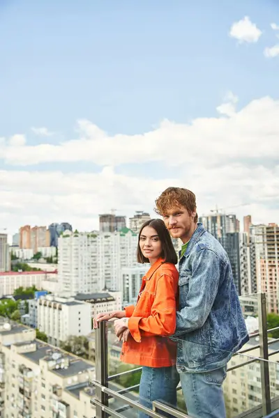 Ein Mann und eine Frau umarmen sich, während sie am Rande eines hohen Gebäudes stehen und die Stadt von unten mit einem Gefühl der Freiheit und Verbundenheit betrachten — Stockfoto