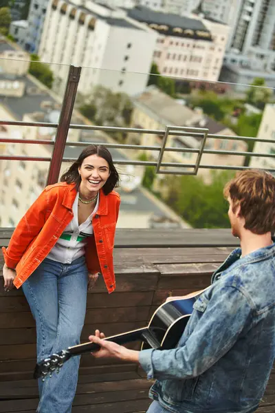 A woman holding a guitar stands gracefully next to a man outdoors, creating a harmonious and musical scene — Stock Photo