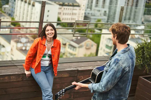 Жінка тримає гітару, стоячи поруч з чоловіком в гармонійній і музичній сцені — стокове фото