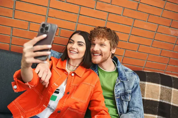 Мужчина и женщина улыбаются и позируют вместе, делая селфи с сотовым телефоном — стоковое фото