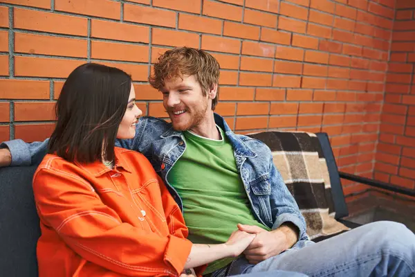 Un uomo e una donna si siedono comodamente su un divano, godendo di un momento di tranquillità insieme — Foto stock