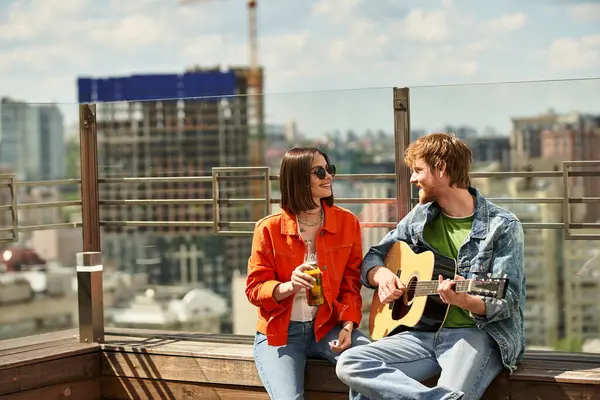 A man and a woman sit on a ledge, engrossed in playing guitars, creating a beautiful harmony amidst a serene backdrop — Stock Photo