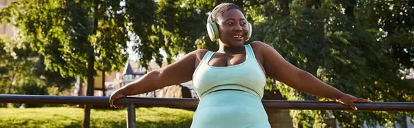 Una mujer afroamericana apoyada en un riel, que encarna la confianza y la relajación al aire libre. - foto de stock