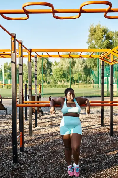 An African American woman in blue sportswear stands confidently at a playground, embodying body positivity and freedom. — Stock Photo