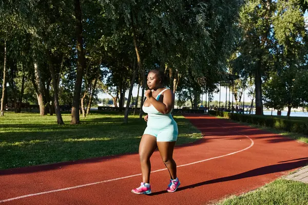 Uma mulher afro-americana em sportswear energeticamente corre ao longo de uma trilha, exalando confiança e poder. — Fotografia de Stock