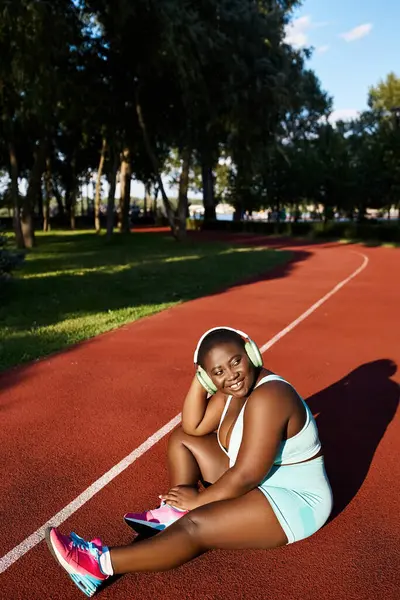 An African American woman in sportswear sitting on a tennis court — Stock Photo