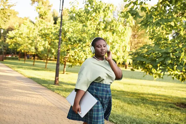Plus size African American woman in casual attire striding along sidewalk — Stock Photo