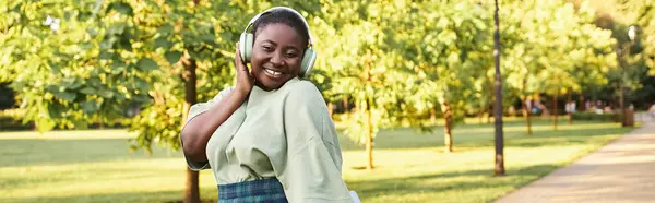 Plus-size African American woman in casual attire, showcasing body positivity, listening to music on headphones — Stock Photo
