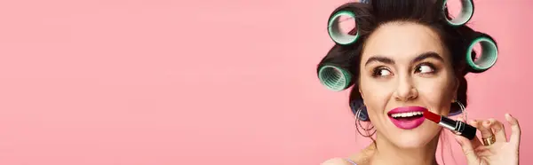 Woman with curlers holding lipstick. — Stock Photo