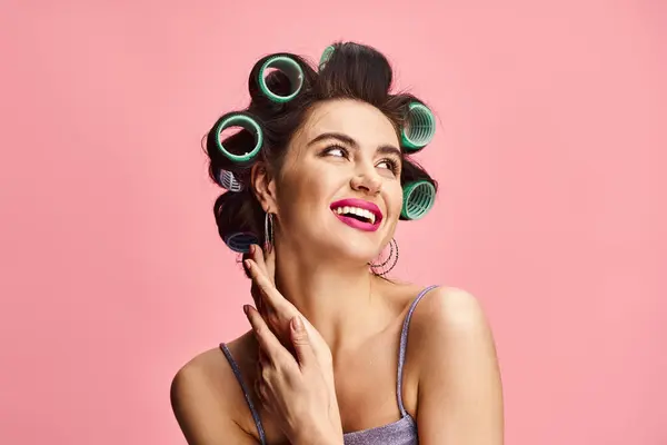 Mujer con rizadores en el pelo posando elegantemente para la cámara sobre un colorido telón de fondo. - foto de stock